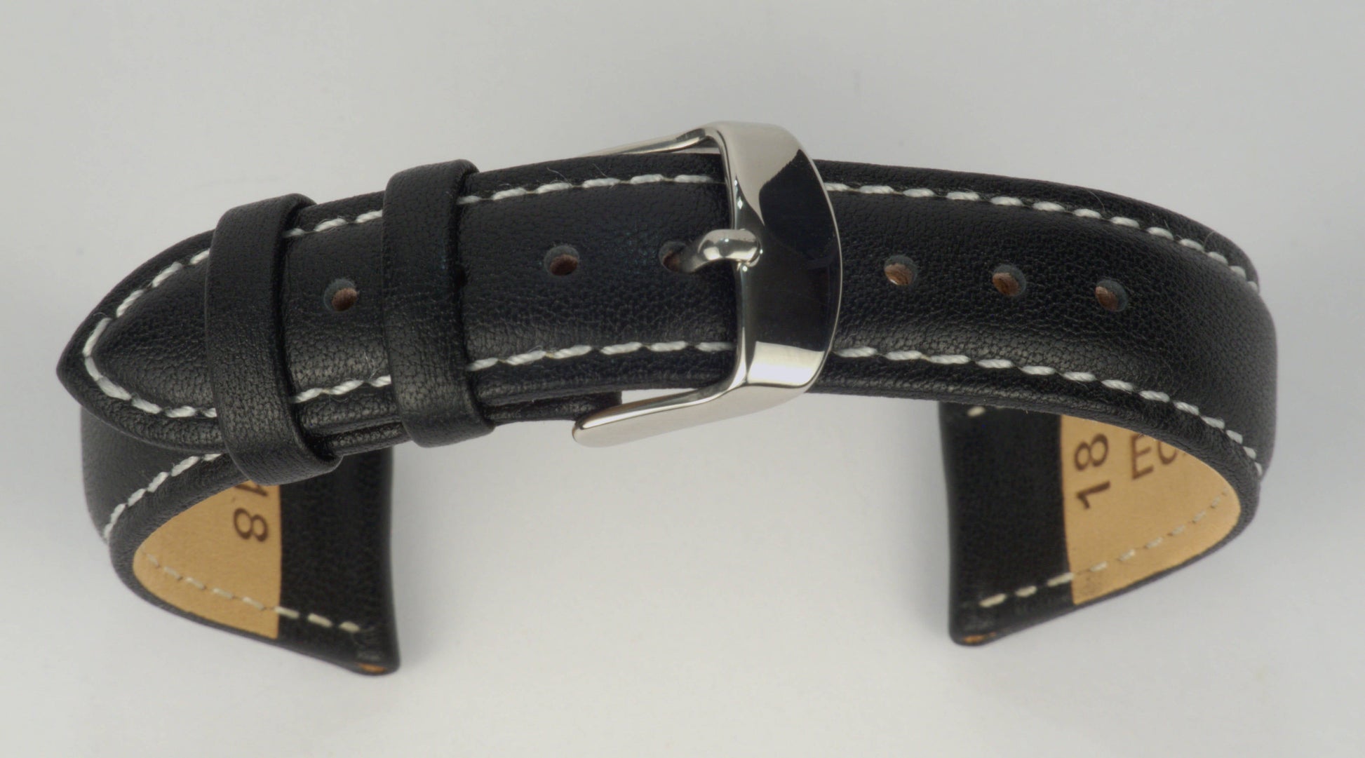 Lederuhrenarmband (Schwarz mit weißer Naht) zu einem Bogen geformt mit weißem Hintergrund. Detaillierte Nahaufnahme.