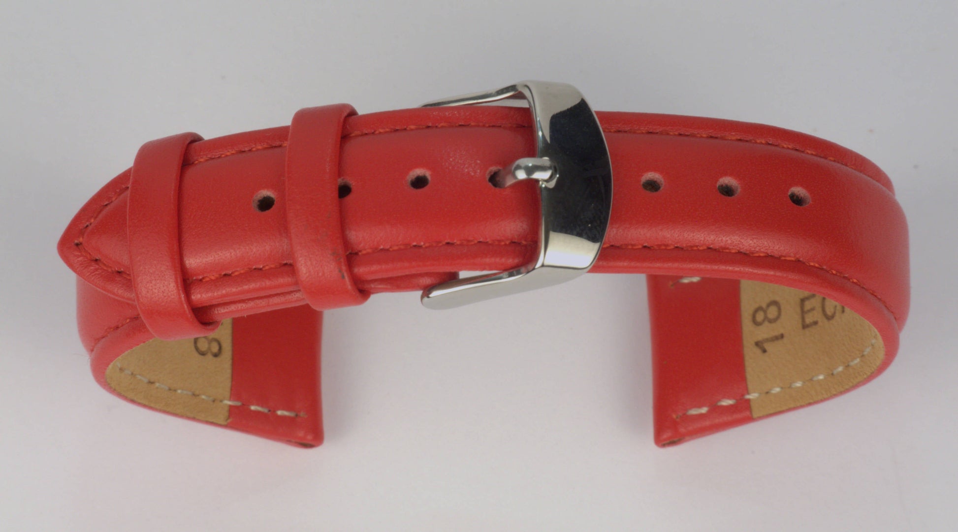 Lederuhrenarmband (Rot) zu einem Bogen geformt mit weißem Hintergrund. Detaillierte Nahaufnahme.