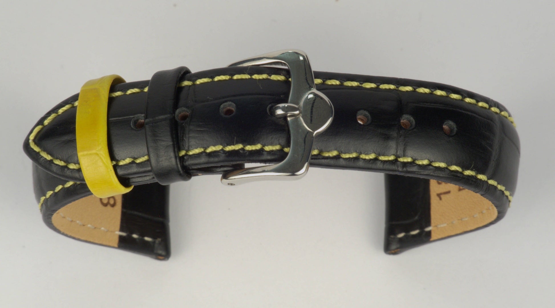 Lederuhrenarmband (Schwarz mit gelber Naht) zu einem Bogen geformt mit weißem Hintergrund. Detaillierte Nahaufnahme.