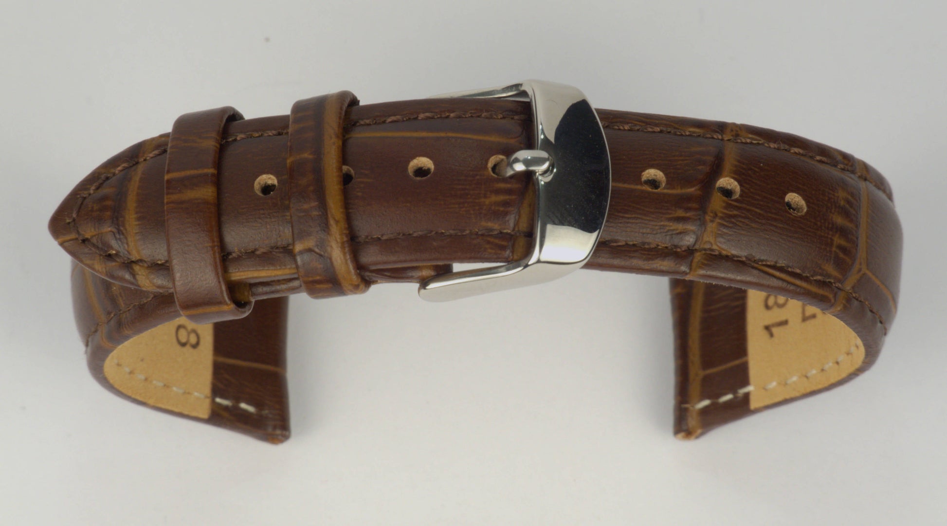 Lederuhrenarmband (Dunkelbraun) zu einem Bogen geformt mit weißem Hintergrund. Detaillierte Nahaufnahme.