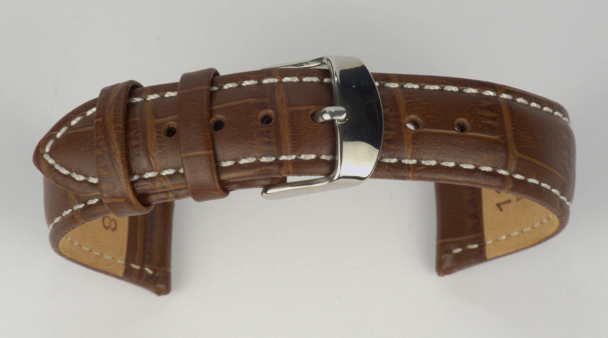 Lederuhrenarmband (Dunkelbraun mit weißer Naht) zu einem Bogen geformt mit weißem Hintergrund. Detaillierte Nahaufnahme.