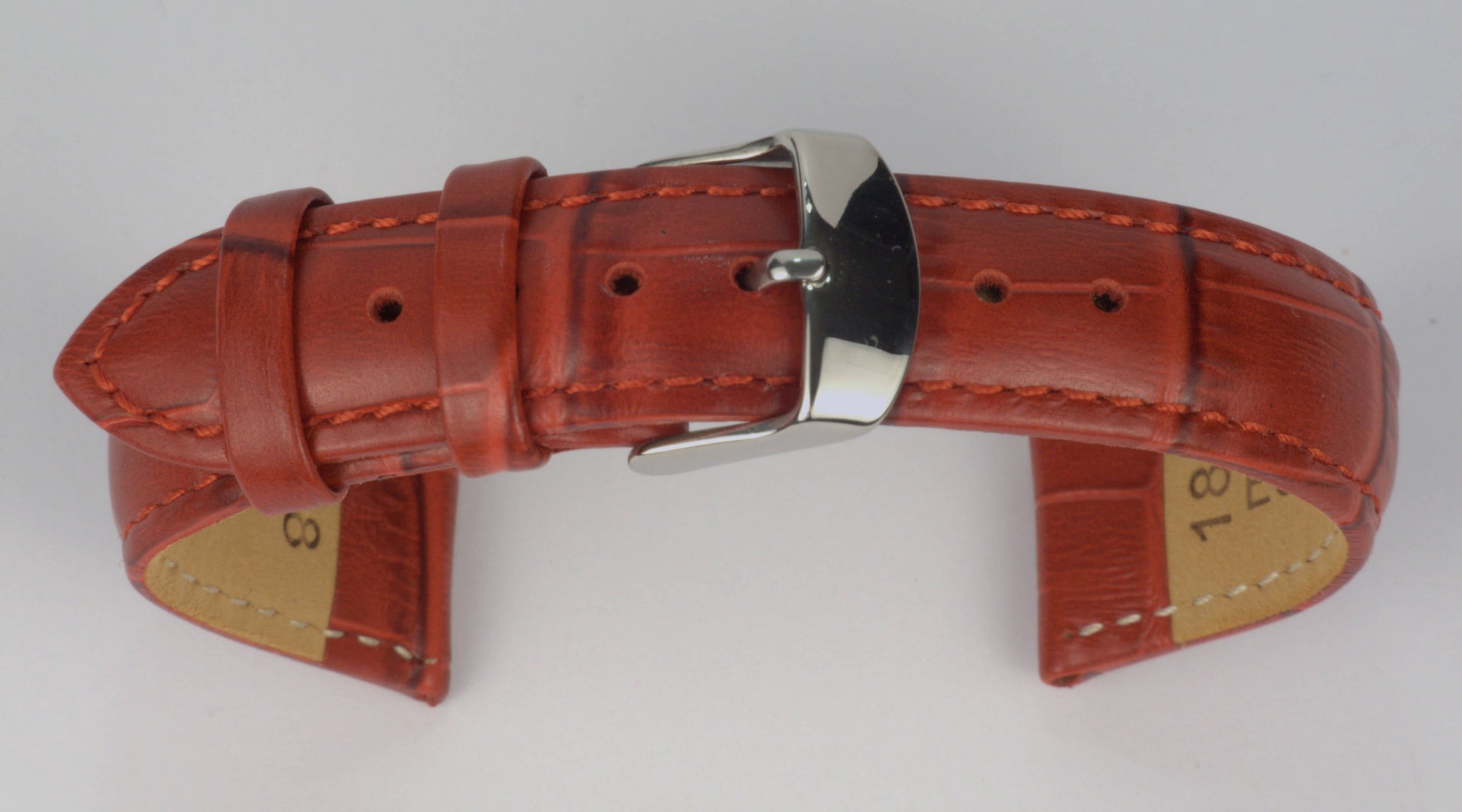 Lederuhrenarmband (Rot) zu einem Bogen geformt mit weißem Hintergrund. Detaillierte Nahaufnahme.