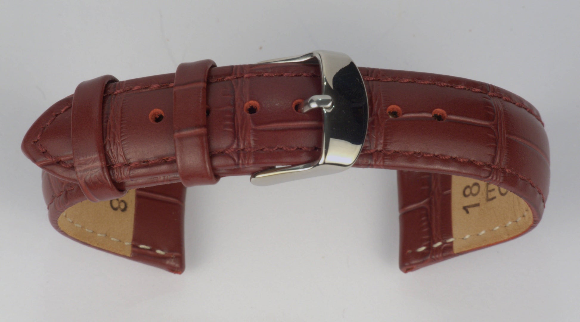 Lederuhrenarmband (Weinrot) zu einem Bogen geformt mit weißem Hintergrund. Detaillierte Nahaufnahme.