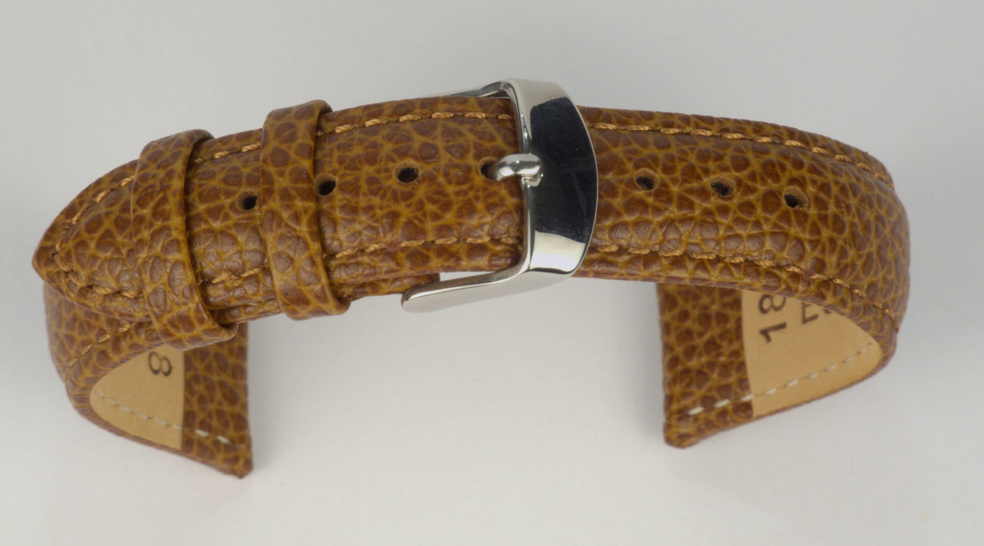 Lederuhrenarmband (Hellbraun) zu einem Bogen geformt mit weißem Hintergrund. Detaillierte Nahaufnahme.