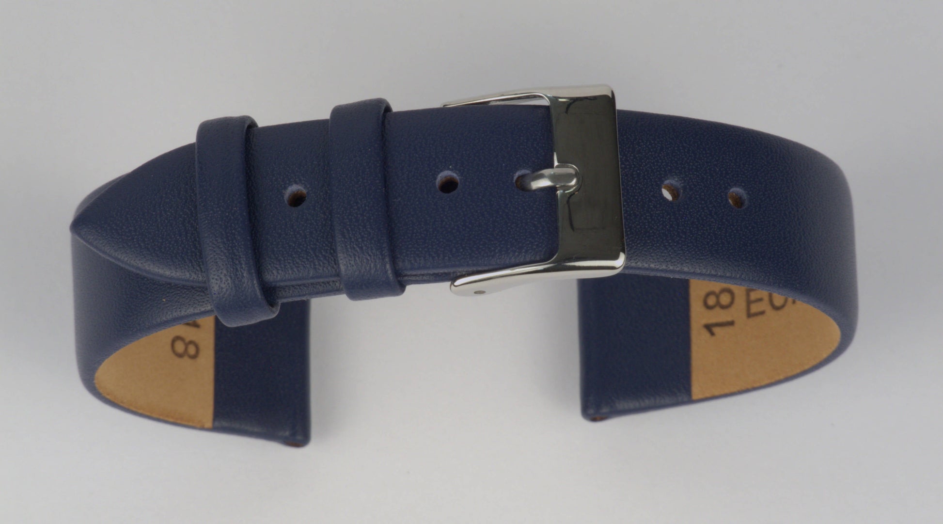 Lederuhrenarmband (Dunkelblau) zu einem Bogen geformt mit weißem Hintergrund. Detaillierte Nahaufnahme.